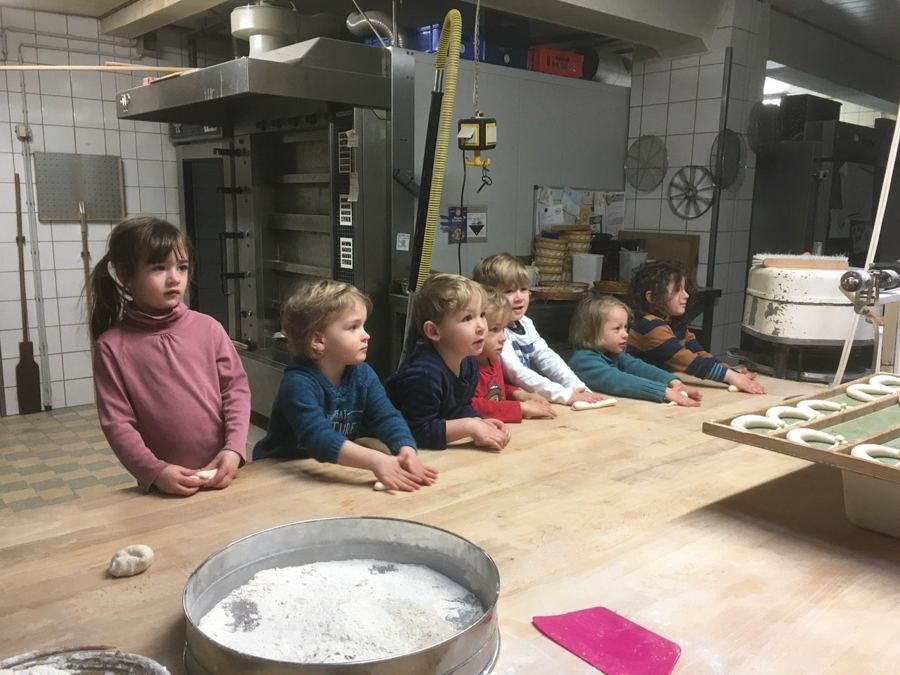 Kinder formen in einer Backstube Teig an einem großen Holztisch