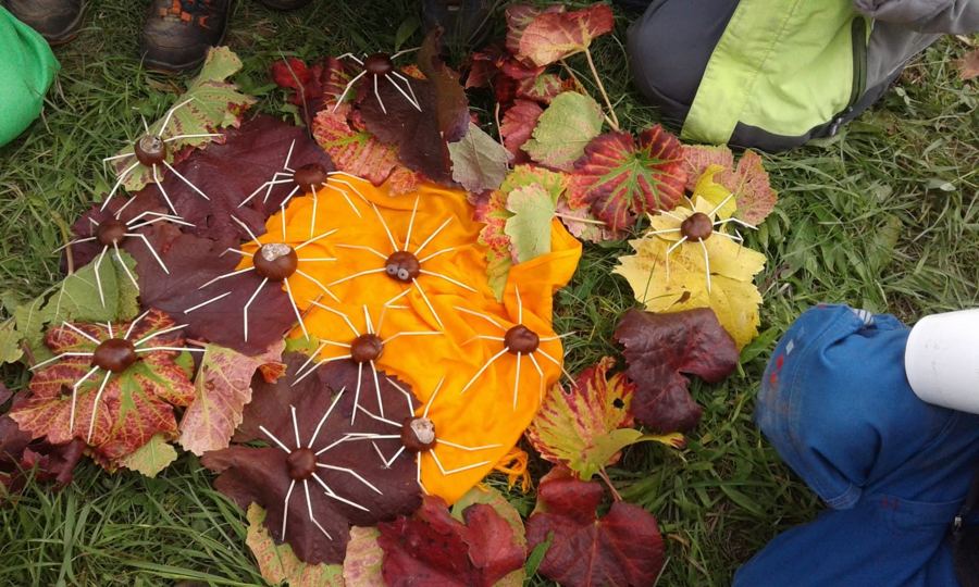 Herbstbild aus bunten Blättern und Kastanien-Spinnen auf einem gelben Tuch