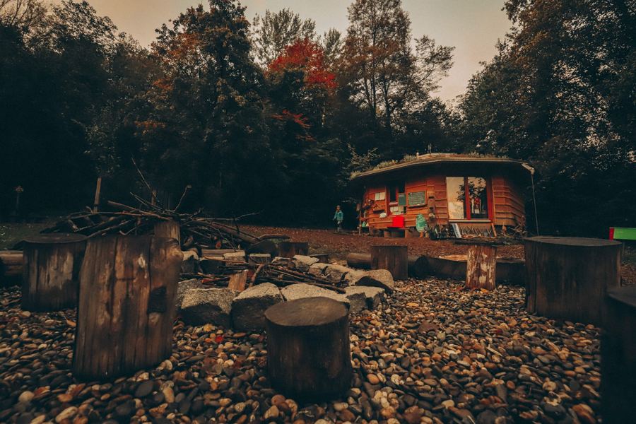 Sitzkreis aus Baumstümpfen mit Feuerstelle vor dem Bauwagen im Herbst